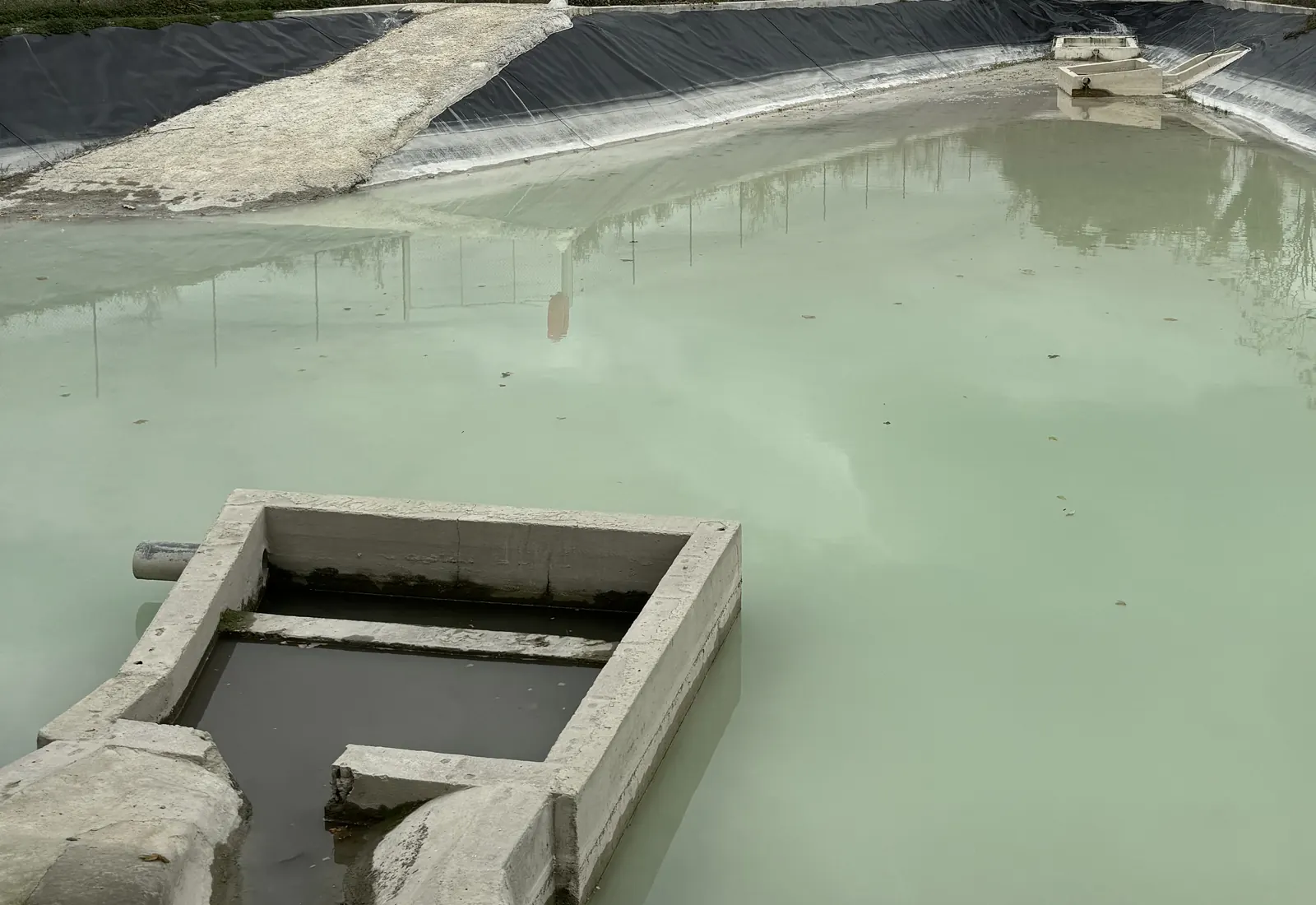 Bassin de décantation étanché par géomembrane avec rampe d'accès pour le curage et ouvrage de sortie en béton